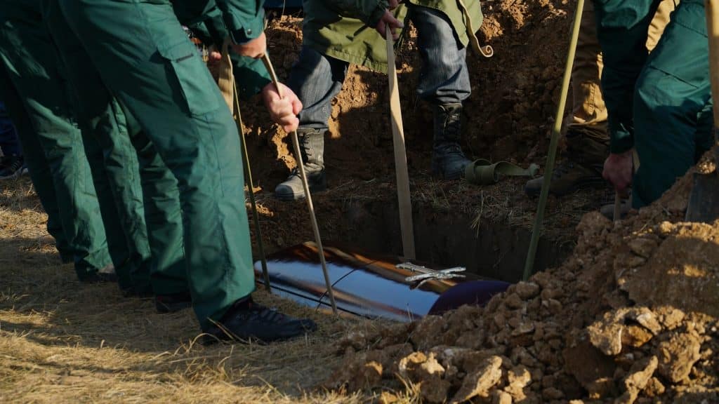 Religion, death and dolor - coffin bearer carrying casket at funeral to cemetery
